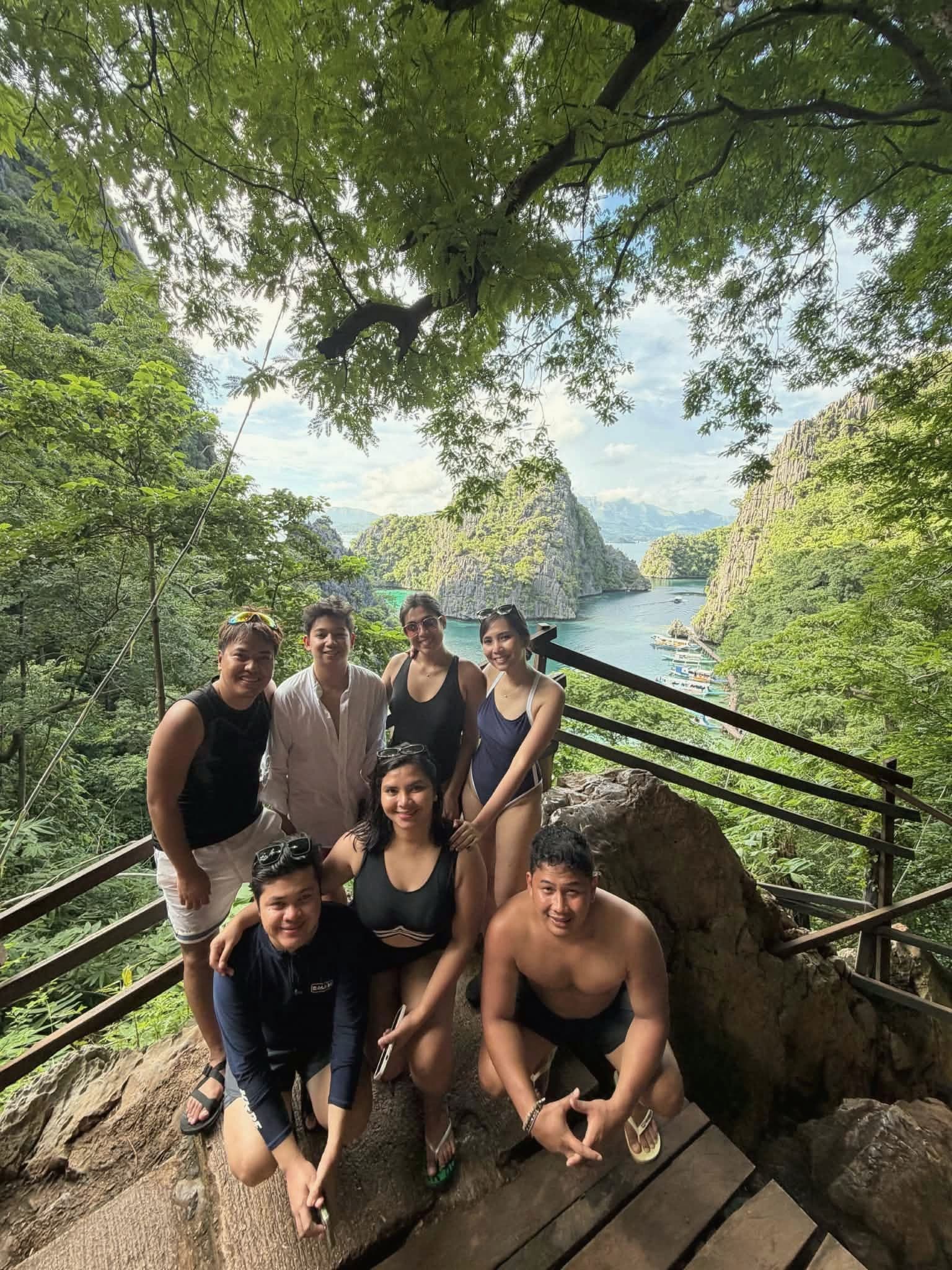 A group of friends posing at the Kayangan Lake viewpoint, with limestone cliffs and the lagoon below